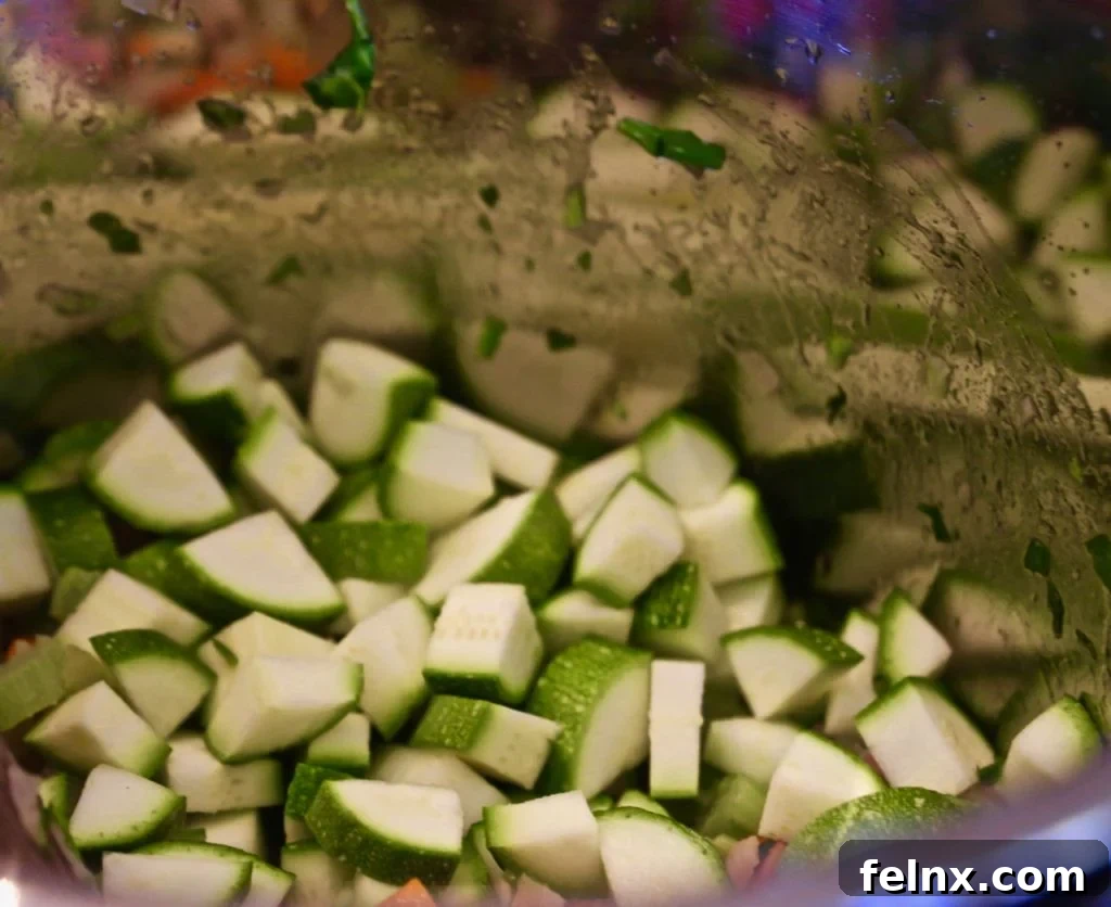 Chopped zucchini being added to the soup