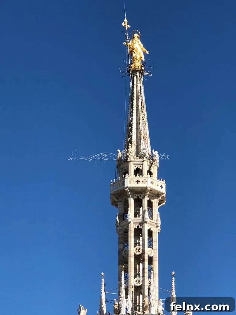 The golden Madonnina statue against a blue sky