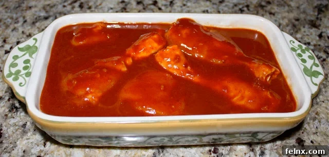 Chicken drumsticks marinating in a red spicy sauce