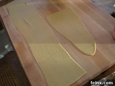 Thinly rolled pasta sheets on a wooden cutting board