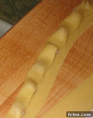 Cutting the pasta strip to separate individual tortellini sections