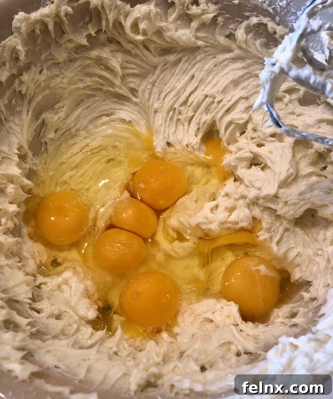 Adding eggs to the cheesecake batter