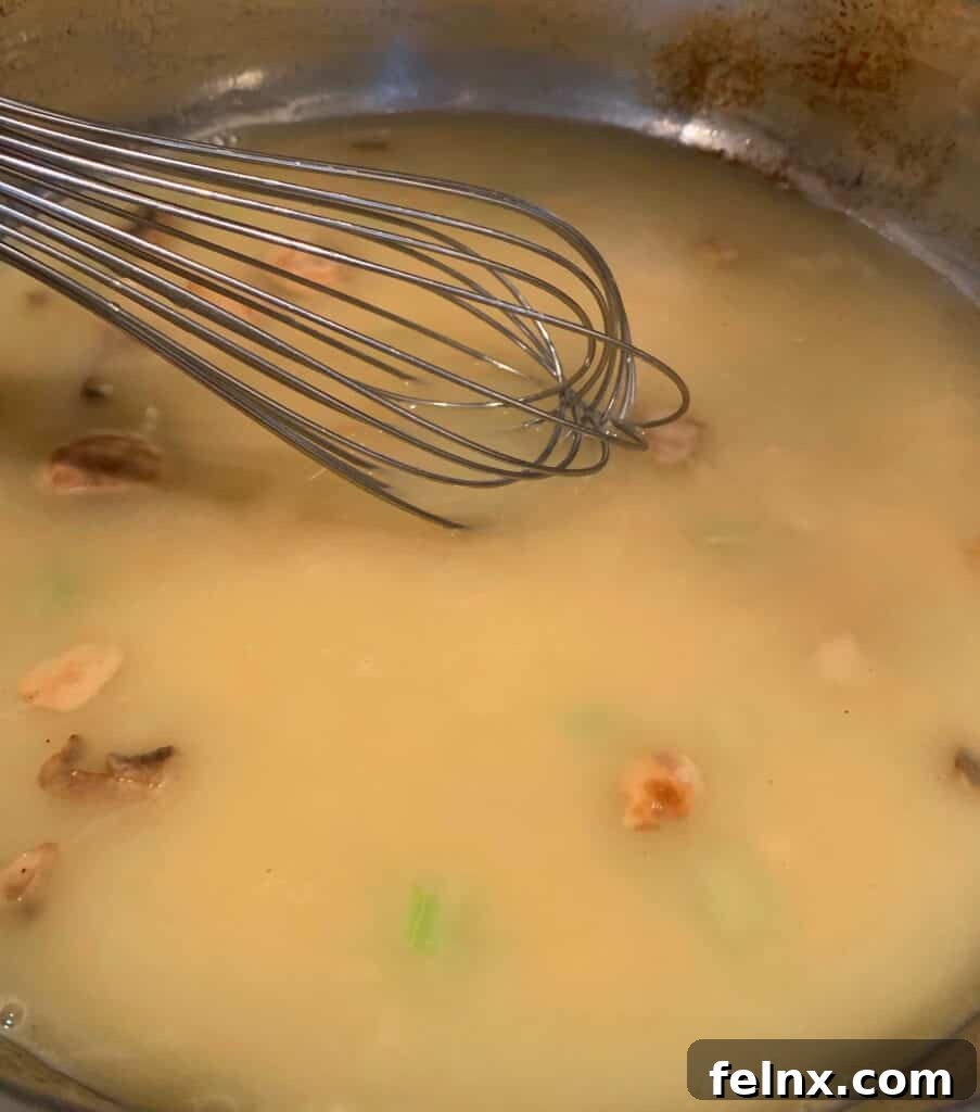 Whisking chicken broth into the sauce