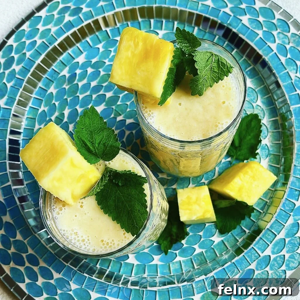 Two glasses of tropical smoothie garnished with mint