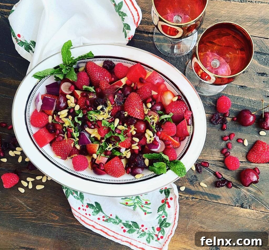 A vibrant bowl of Christmas Red Fruit Salad with a dollop of lemon cream sauce on top
