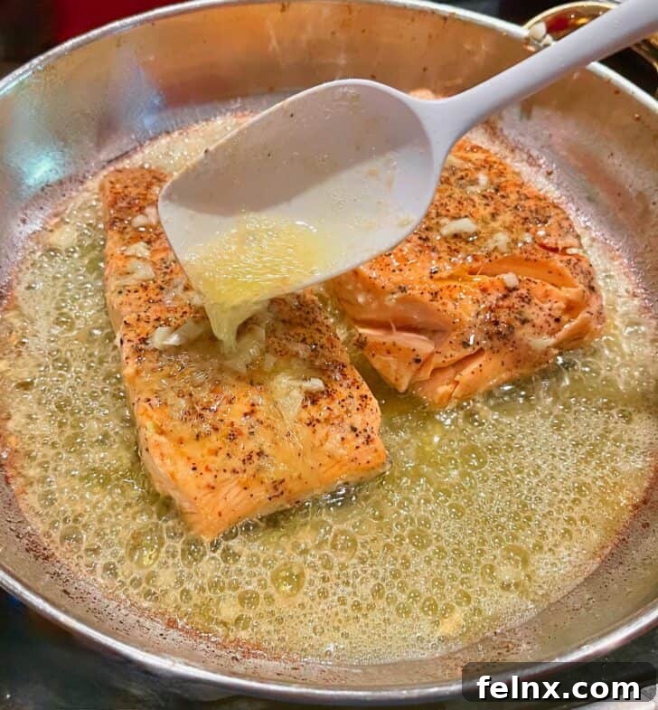 Basting salmon with garlic butter in a skillet