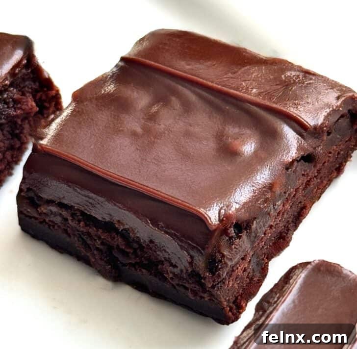 A close-up of a rich chocolate brownie with a thick layer of ganache frosting