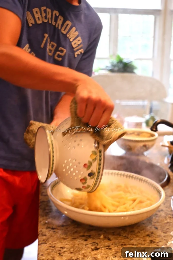 Straining the bucatini pasta into a large bowl