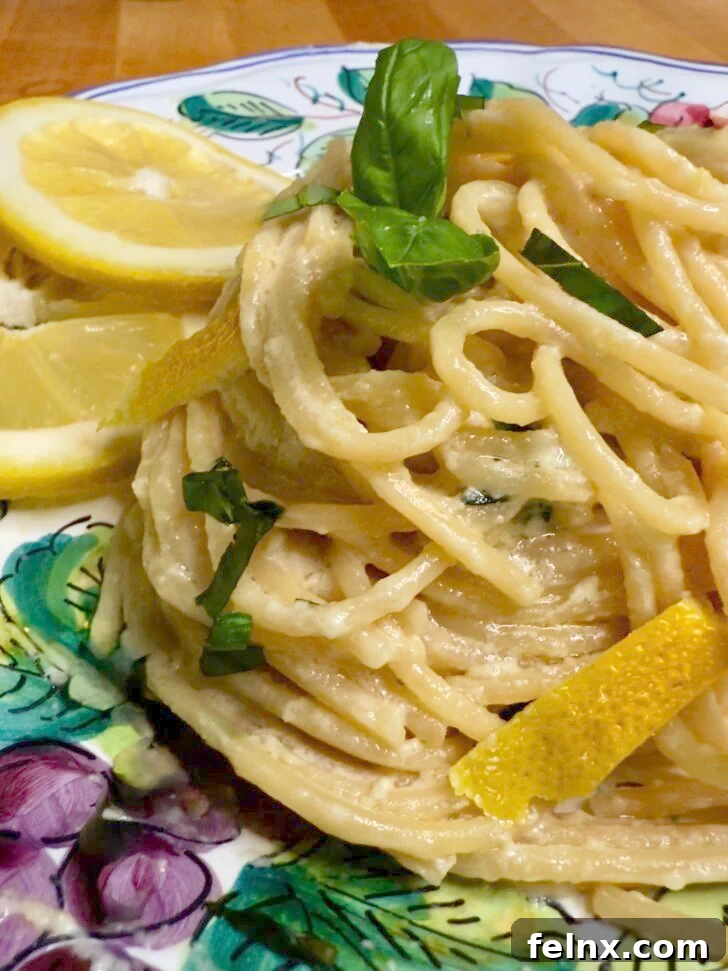 A vibrant bowl of Pasta al Limone, showcasing spaghetti coated in a creamy lemon sauce, garnished with fresh basil.