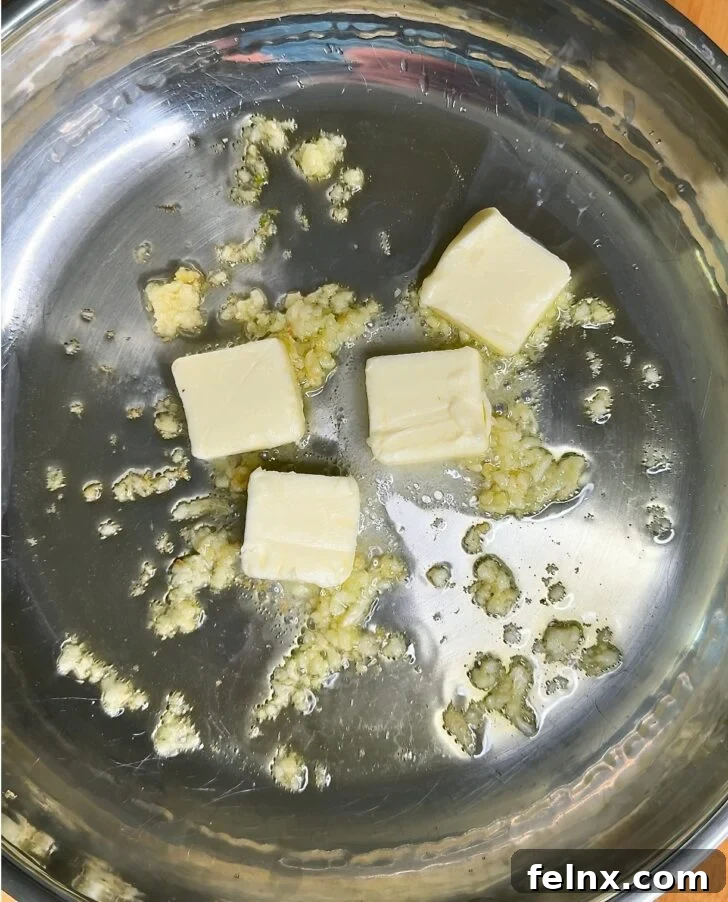 Butter melting into olive oil and garlic in a pan.