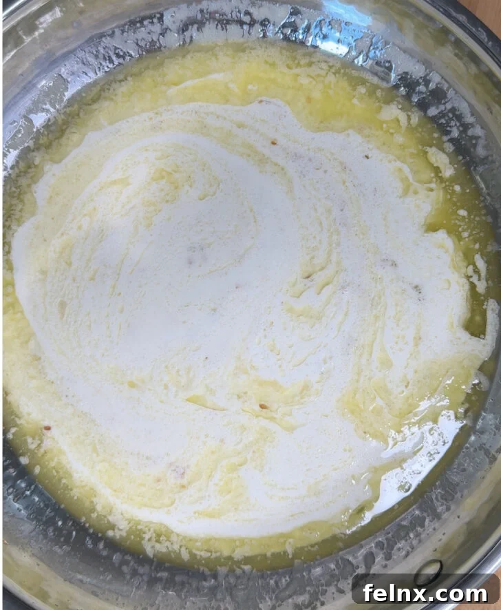 Heavy cream being stirred into the lemon butter sauce.