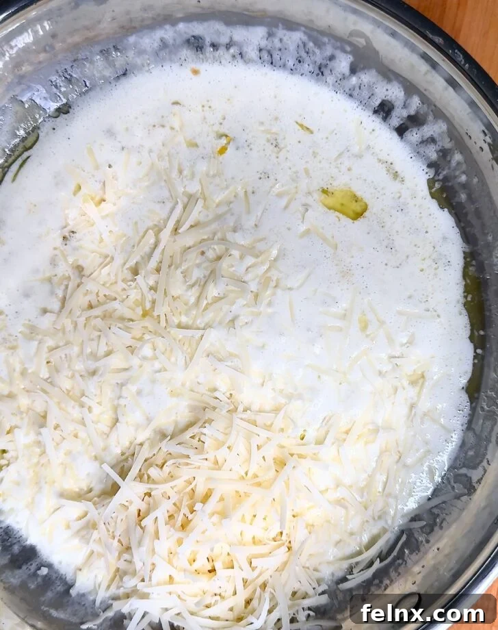 Parmesan cheese being added to the creamy lemon sauce.
